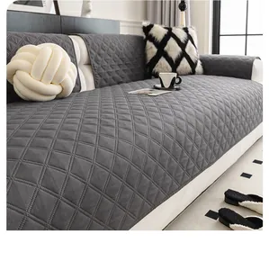 Detailed view of dark grey quilted sofa cover with diamond patterns in a cozy living room