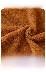 Détail macro du tissu en laine d'agneau douce à texture sherpa dense marron caramel
