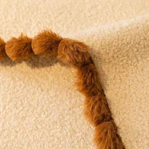 Plush teddy fleece sofa cover with decorative brown pom-pom edges and detailed stitching