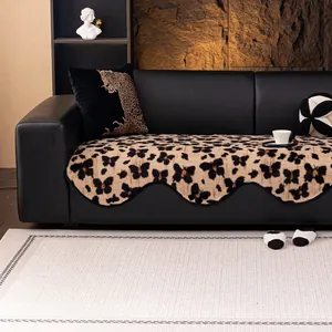 Thick plush leopard and butterfly sofa cover with scalloped edges on black leather sofa