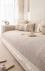 Detail of cream chenille sofa cover with decorative lace trim and plush pom-poms