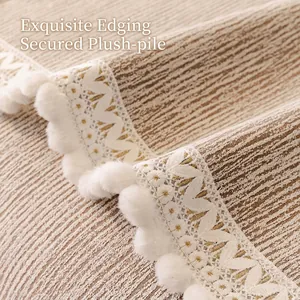 Minimalist beige sofa cover with vertical texture, white lace edges and pom-poms