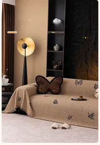 Detail of cream sofa cover with black butterfly patterns and fringe edge