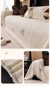 Close-up of thick beige plush sofa cover with grey butterfly patterns and woven tassels