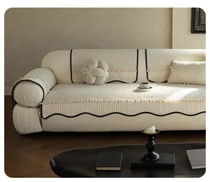 Detail of off-white chenille sofa cover showing black wave trim and small pompom tassels