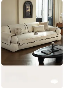 Detailed texture of cream chenille sofa cover with black wavy borders and tassel trim