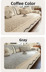 Detail of chenille sofa cover with pleated skirt hem and decorative pompoms in grey