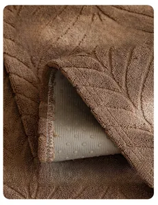 Detailed view of brown sofa cover featuring leaf texture and white anti-slip backing