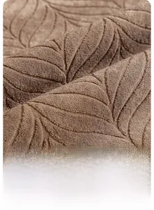 Close-up of brown sofa cover fabric featuring embossed leaf patterns and soft texture
