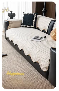 Detail of cream plush sofa cover with wavy edges and brown piping on black leather