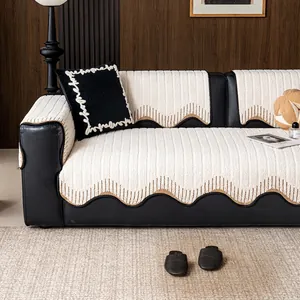 Minimalist creamy velvet sofa cushion with brown scalloped edges on a dark leather sofa