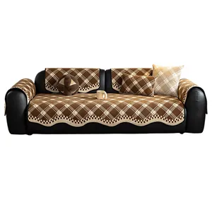 Brown checkered chenille sofa cover set with scalloped edges on a black leather sofa