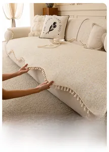 Close-up of beige chenille sofa cover with pom-pom fringe and striped texture fabric