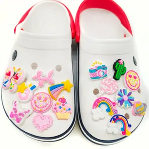White clog shoes featuring colorful DIY charms like butterflies and rainbows on plain background