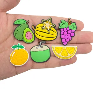 Detailansicht von Frucht-Schuhanhängern aus PVC in der Hand zur Größendarstellung