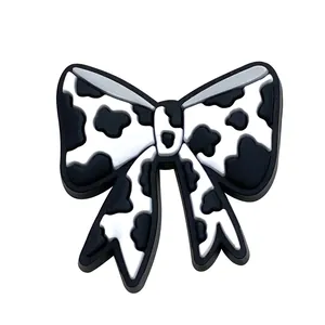 Detail of PVC bow-shaped shoe charm featuring a classic black and white cow print pattern