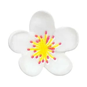 Detailed view of white floral shoe charm with yellow center and thick fabric texture