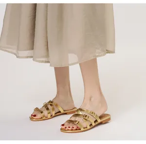 Detailed macro view of champagne gold flat sandals with thin straps and metallic buckles