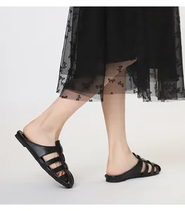 Detalle de mules planos trenzados negros con diseño calado y punta cerrada formal