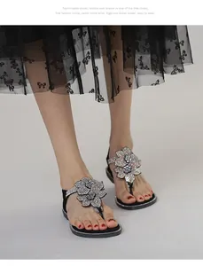 Detail of flat flip-flop sandals featuring large rhinestone flowers and sparkling straps