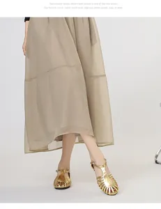 Detalle de sandalias romanas tejidas doradas con falda larga beige de estilo verano