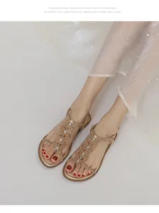 Close-up of champagne gold flat sandals with sparkling rhinestone butterfly T-strap design