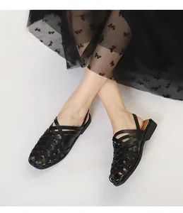 Detalle de sandalias de cuero trenzado negro con diseño calado de tiras cruzadas