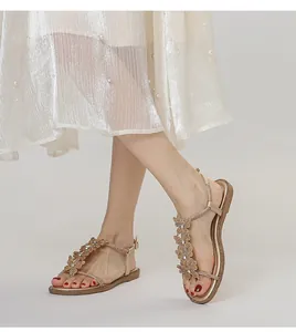 Detail of gold T-strap flat sandals with rhinestone butterflies and ankle buckle strap