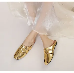 Detail shot of gold metallic woven mule sandals worn with an elegant white lace dress