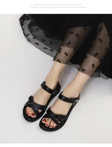 Draufsicht auf schwarze flache Sandalen mit Kreuzriemen und goldenen Schnallen