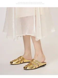 Detail of gold hollow woven mules with metal buckle on white mesh skirt background