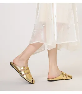 Close-up of gold metallic flat mule sandals with woven straps and side buckle details