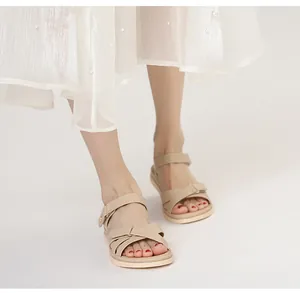 Detailaufnahme der beigen flachen Sandalen mit Kreuzriemen und Klettverschluss am Fuß