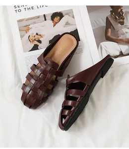Detalle del cuero trenzado burdeos en los clásicos zuecos planos para mujer elegante