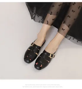 Detail of black woven leather mules with gold buckle worn with a polka dot skirt