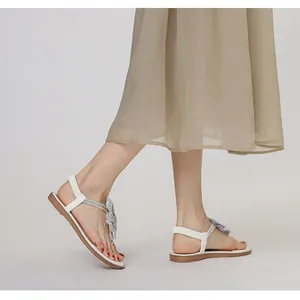 Detail view of white T-strap sandals with silver glitter floral accents and elastic heel