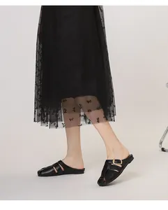 Detail of black matte leather closed-toe flat mule with gold buckle and cutout strap design