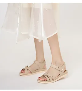 Detail der beigen flachen Sandalen mit Riemchen-Design und Klettverschluss am Model