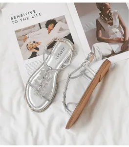 Detailed close-up of silver flat sandals featuring rhinestone butterfly and buckle strap