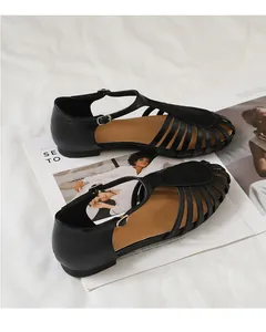 Vista detallada de sandalias romanas negras tejidas huecas sobre fondo de revista de moda
