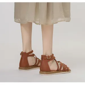 Nahaufnahme brauner Römersandalen mit geflochtenen Details und hinterem Reißverschluss