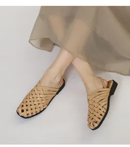 Primer plano de sandalias planas tejidas a mano en beige con correas de cuero caladas