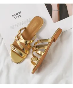 Close-up of golden multi-strap flat sandals with metallic buckles and brown sole