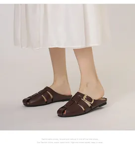Close-up of brown woven leather mule sandal with adjustable gold buckle on a model