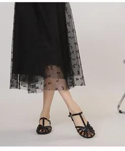 Nahaufnahme von schwarzen geflochtenen T-Steg-Sandalen mit Durchbruchmuster und Schnalle