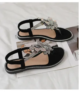 Detailed view of black flat sandals with 3D floral accents and shimmering rhinestones