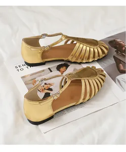Primer plano de sandalias romanas doradas con diseño tejido y correas de tobillo