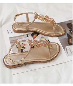 Detail of champagne gold flat sandals featuring crystal butterfly buckles and ankle strap