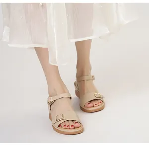 Dettaglio di sandali beige con zeppa con fibbie dorate e suola platform effetto legno