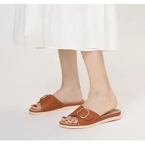 Detailaufnahme brauner Leder-Sandalen mit goldener Schnalle und weicher Sohle